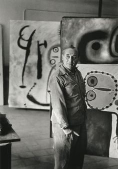 black and white photograph of a man standing in front of some art on the wall