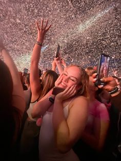 a group of people at a concert with confetti on the ceiling and hands in the air