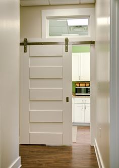 an open door leading to a kitchen with white cabinets