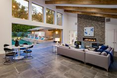 Open plan Beverly Hills modern luxury home for indoor outdoor west coast lifestyles opens up the living room to the pool terrace with sliding glass walls & windows.