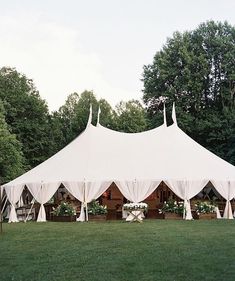 a large white tent set up in the middle of a field with tables and chairs