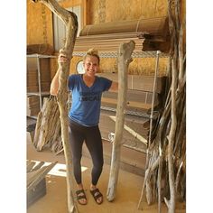 a woman is standing in front of some tree branches with her hands on the poles