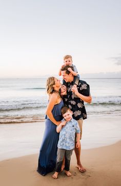 a family standing on the beach at sunset with one child in his arms and two adults around him