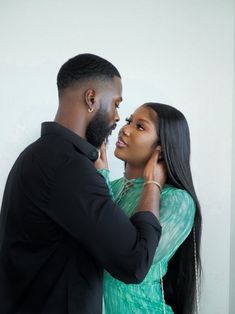 a man and woman standing next to each other in front of a white wall together