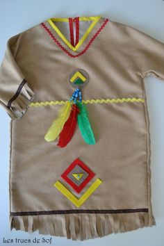 a child's native american dress made out of fabric and beads with feathers on it