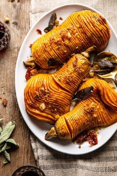 three stuffed sweet potatoes on a white plate with spoons and spices around them next to some dried herbs