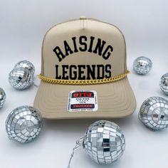 The Coco & Rho Original Raising Legends Trucker Hat is a staple for everyone. Adorned with a gold chain. The lettering is a soft velvet that gives it a raised and elevated look and feel. Made with a mesh back and adjustable strap for universal sizing! Introducing our exclusive Trucker Hat with a twist - each hat is a masterpiece, adorned with carefully curated patches for a unique touch. Crafted for the bold and the adventurous, this hat is more than an accessory; it's a statement of individuali Adjustable Gold Snapback Baseball Cap, Gold Adjustable Snapback Baseball Cap, Adjustable Gold Snapback Hat, Adjustable Gold Snapback Cap, Gold Adjustable Snapback Hat, Gold Snapback Hat With Curved Brim, Gold Adjustable Snapback Hat With Curved Brim, Gold Curved Brim Adjustable Snapback Hat, Gold Snapback Hat With Adjustable Flat Brim