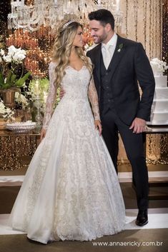 a bride and groom standing next to each other in front of a chandelier