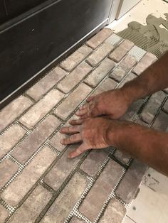 a man laying tile on the floor with his hands resting on it's side