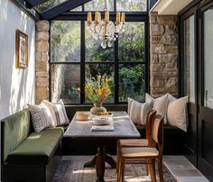 a room with a table, couches and chandelier hanging from the ceiling