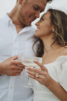 a man and woman standing next to each other holding wine glasses