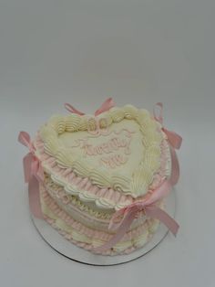 a heart shaped cake with pink ribbon on top