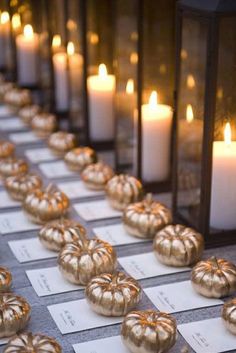 candles are lined up on a table with cards and place names in front of them