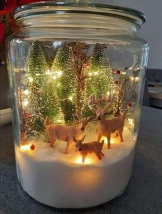 a glass jar filled with christmas lights and deer figurines