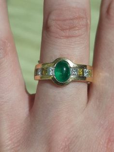 "A vintage 18ct gold emerald, yellow sapphire, and diamond ring. The ring is not Hallmarked, but is stamped \"18K.\" The cabochon cut emerald is rub-over set at the centre of the ring, and measures 7 x 5mm's. On each shoulder set in a channel are two square cut yellow sapphires, and two princess cut diamonds. Each yellow sapphire measures 2.5 x 2.5mm's. There are four yellow sapphires,and four diamonds in total. The total approximate weight of the diamonds is 0.50ct's. An absolutely stunning, and unique ring.  A one of a kind conversation piece. This ring is a finger size O, but we can make it bigger, or smaller." Vintage Green Emerald Ring With Brilliant Cut, Heirloom Green Sapphire Ring With Diamonds, Hallmarked Emerald Ring With Diamonds, Two Princess, Wishbone Ring, Amethyst And Diamond Ring, Sapphire And Diamond Ring, Unique Ring, Square Cut