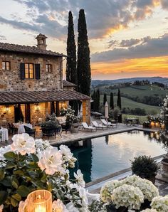 an outdoor pool surrounded by white flowers and candles in front of a large stone building