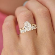 a woman's hand with a diamond ring on top of her finger and an engagement band