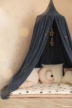 a bed that has some pillows on it and a curtain over the top with stars