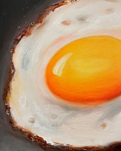 an egg is shown in the middle of a painting on a black surface with white and orange paint