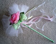 there is a pink rose on the top of a green stick with white tulle