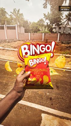 a person holding up a bag of chips with the word bingo written on it