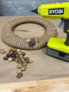 a corded power drill sitting on top of a table next to rocks and a rope