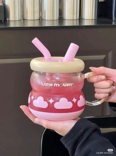 a person holding a pink cup with straws in it and the lid has hearts on it