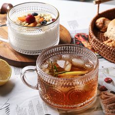 two glasses of tea on a table with bread and fruit