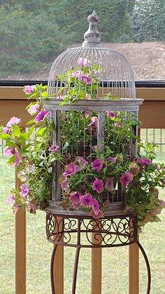 a birdcage filled with flowers on top of a balcony