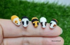 four tiny crocheted animals are sitting on someone's finger in the grass