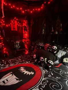 a bedroom decorated in black and red with skulls on the bedspread, lights strung from above