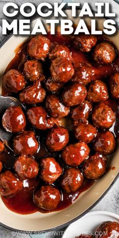 meatballs with sauce in a white bowl on top of a table next to a spoon