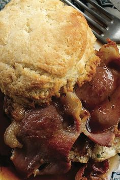 a close up of a plate of food with meat and biscuits on it next to a fork