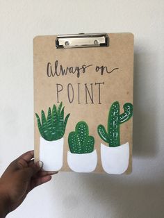 a hand holding up a clipboard with three small cactuses on it that says, always on point