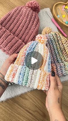 a person holding a knitted hat on top of a wooden table next to other items