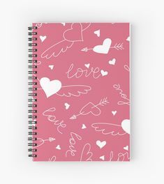 a pink notebook with white hearts and arrows on the cover that says love written in cursive writing