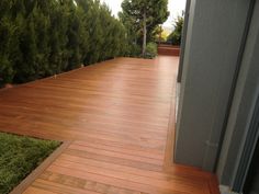 a wooden deck with grass and trees in the background