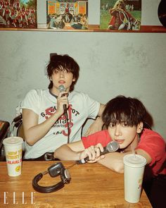 two young men sitting at a table with microphones