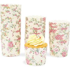 three cupcakes and two vases with flowers on the sides, one has a frosted icing