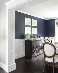 a dining room with blue walls and white furniture in the center, along with dark wood flooring