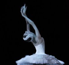 a ballerina is dressed in white and holding her arms up to the side with one hand