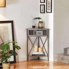 a table with candles and pictures on the wall next to a plant in a vase