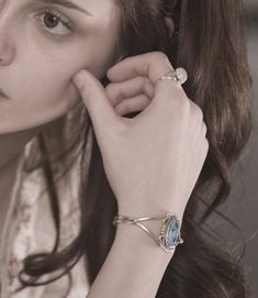 a woman is holding her hand up to her ear and looking at the camera while wearing a ring