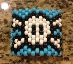 a close up of a beaded object on a counter top with blue and black beads