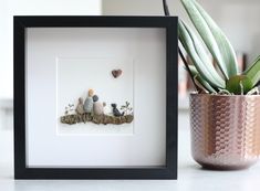 a potted plant sitting on top of a white table next to a framed photo