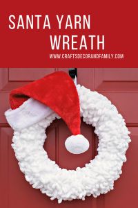 a santa yarn wreath hanging on a red door with the words santa yarn wreath above it