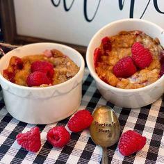 two white bowls filled with raspberries on top of a checkered table cloth