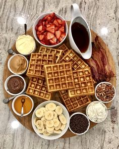 waffles, fruit, and other foods are arranged on a wooden platter