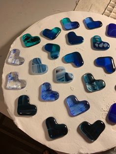 a white plate topped with lots of blue and black heart shaped glass pieces on top of it