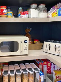 a microwave sitting on top of a wooden shelf next to other food items and containers